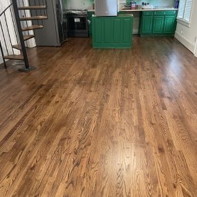 Staining new wood floors requires artisans start at the farthest corner of the room and work back. Apply the stain with the wood grain. Dry for several hours over night. Lightly sand the floor with 200 fine-grid paper to remove bubbles.