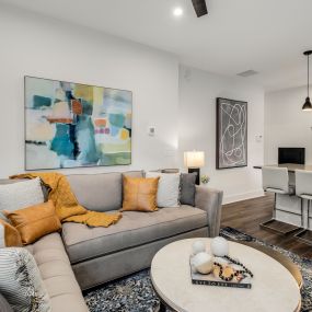 Renovating this living space involved breaking down walls to make an open plan area. Functional and stylish furniture prioritizes comfort. Striking artwork completes this home renovation.