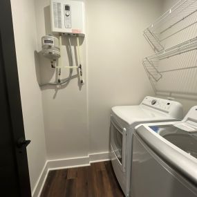 Tankless water heaters are energy efficient and save on space, as we see installed in this student house laundry room.