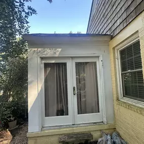 Say goodbye to this weathered French door! Soon, it will be replaced with a sleek, glass-grid French door as part of the new sunroom addition. Fresh exterior siding, charming wood steps, and newly laid lawn will complete the updated space.