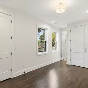 The oversized wardrobe space in the bedroom features large, sturdy doors that open to reveal ample storage. Complemented by luxury vinyl plank flooring, the design adds a durable touch that enhances the overall elegance of the space.