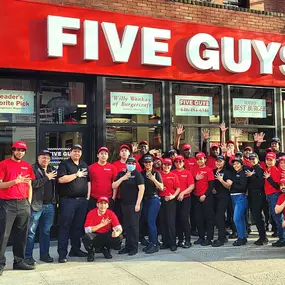 Employees pose for a photograph outside the restaurant ahead of the grand opening of the Five Guys location at 188 2nd Avenue in New York City.