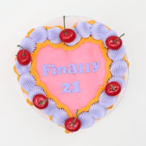 A heart-shaped cake with a bright pink frosting center and the message 