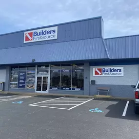 The front entrance of the Builders FirstSource Chesapeake location, specializing in decking, millwork, and building materials. The storefront features large signage, product displays, and accessibility parking, welcoming contractors and homeowners for all their construction supply needs.