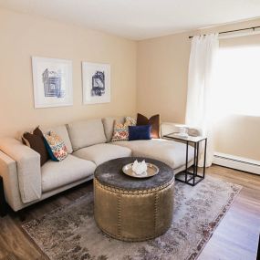 Spacious living room with window coverings and hardwood style flooring.