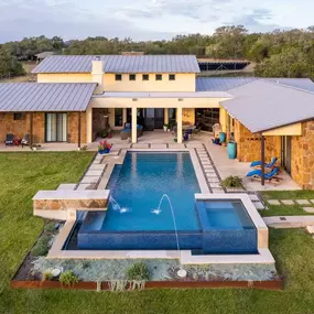 Pool renovation added a negative edge, river rock between coping and salt etched pavers, laminar jets, glass tile and grey plaster with jewel glass beads