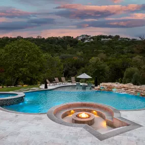 A pool, spa, fire pit, stone waterfalls, and tanning ledge  overlooking the Texas Hill Country