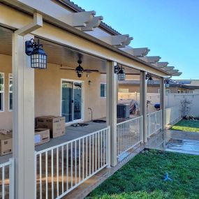 Alumawood patio cover with electrical lighting, wrought iron fence panels, and gate.