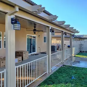 Alumawood patio cover with electrical lighting, wrought iron fence panels, and gate.