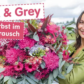 Frau haelt großen pink und graufarbigen Herbststrauss