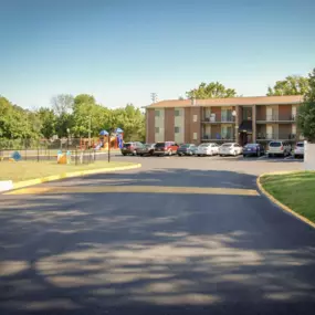 A freshly paved parking lot in front of a brick apartment building with cars parked along the side.