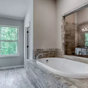 Owner's suite tile bathroom with soaking tub in the DRB Homes Traditions at Crystal Lake community