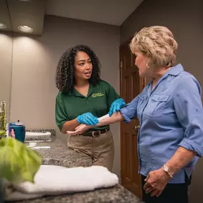 Home Instead Care Giver and their client in the bathoom, putting on a band aid
