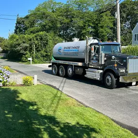 Shore Things Environmental septic truck in front of a house with trees in background and green grass in foreground