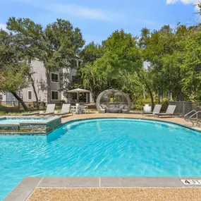 A swimming pool surrounded by trees and chairs