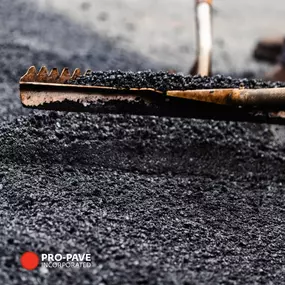 Asphalt being spread with metal rake