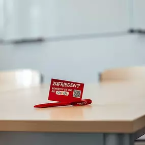 Beispiel Unterrichtsraum vor Ort mit Tisch, Stühlen und White Board an der Wand.