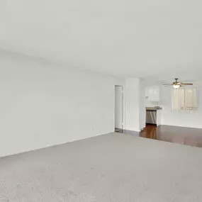 an empty living room with white walls and a ceiling fan