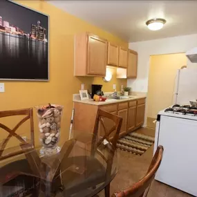 Bright kitchen and dining area with wood cabinetry and gas appliances at Country Meadows Apartments in Ypsilanti, MI.