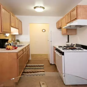 Galley-style kitchen with ample cabinet space and gas range at Country Meadows Apartments in Ypsilanti, MI.