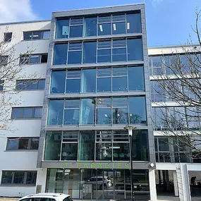 Das moderne Gebäude des Gesundheitszentrums Jena, mit großzügiger Glasfassade und zentralem Eingangsbereich.