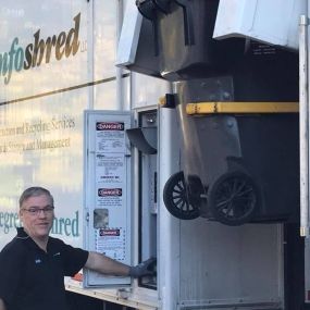 An Infoshred mobile shredding truck with a shredding collection bin in the lift