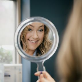 A patient of Matthews Dentistry looking into a mirror.