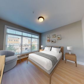 A bedroom with hardwood-style flooring and a large window at The Lofts at Saratoga Blvd.