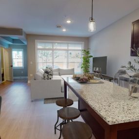 A kitchen with an island leading to a living room with a large window in a loft apartment at Lofts at Saratoga Blvd.