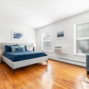 A bedroom with hardwood-style flooring and two windows with ample natural light.