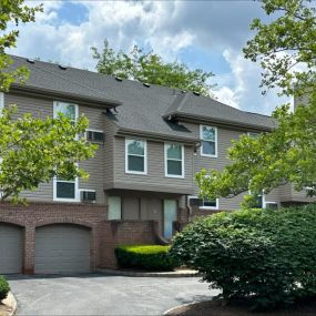 A driveway leads to an exterior view of the Everly Roseland apartment building with trees and garages.