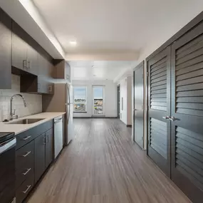 A hallway with wooden storage cabinets, wood-inspired flooring and a built-in microwave at Elevation16 in Seattle, WA