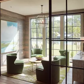 a living room with green chairs and a table and glass doors