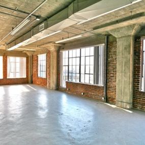 an empty room with brick exposed walls and long windows