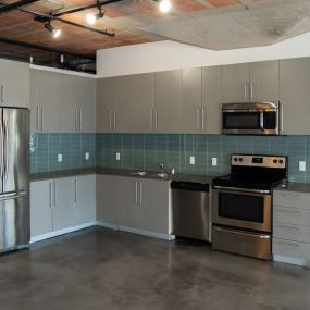 an empty kitchen with stainless steel appliances and gray cabinets