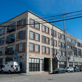 a large brick building with cars parked in front of it on a city street