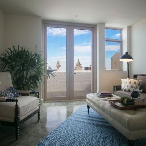 A living room with a view of the balcony and a couch and chair