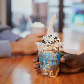Two ice cream sundaes being enjoyed by two people at table at a Ben & Jerry's ice cream shop.