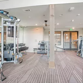 a gym with weights and cardio machines and a glass door