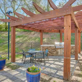 a patio with a table and chairs under a wooden pergola at Spring Creek Apartments