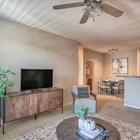 a living room with a ceiling fan and a tv at Spring Creek Apartments