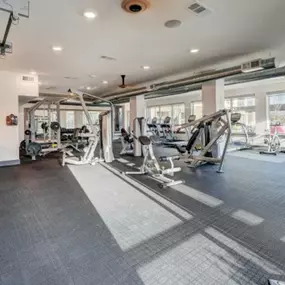 a gym with weights and other equipment in a building with windows at The Jane at Preston Trail