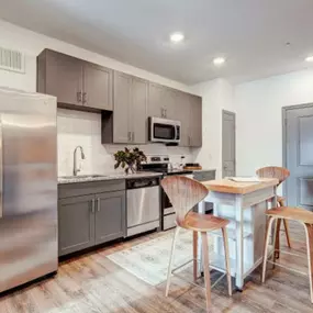 a kitchen with stainless steel appliances and a bar with chairs at The Jane at Preston Trail