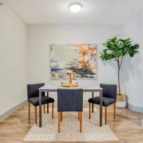 a dining room with a table and chairs and a painting on the wall