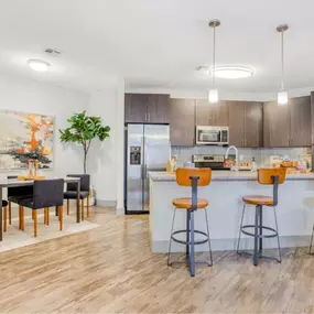 a large kitchen with a bar and a dining area with chairs