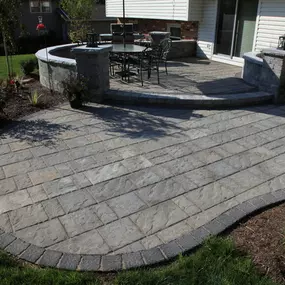 Dual leveled paver patio with seating wall surrounded by landscape beds.