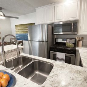 a kitchen with stainless steel appliances and a bowl of oranges