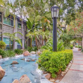 a sidewalk with a water feature in front of a building