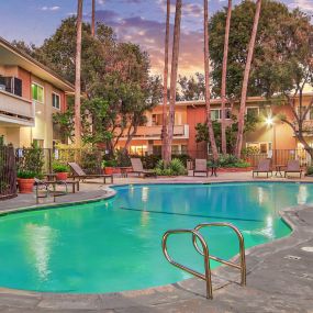 a resort style swimming pool at night with a hotel in the background