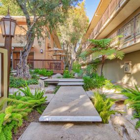 a walkway between two buildings with trees and plants